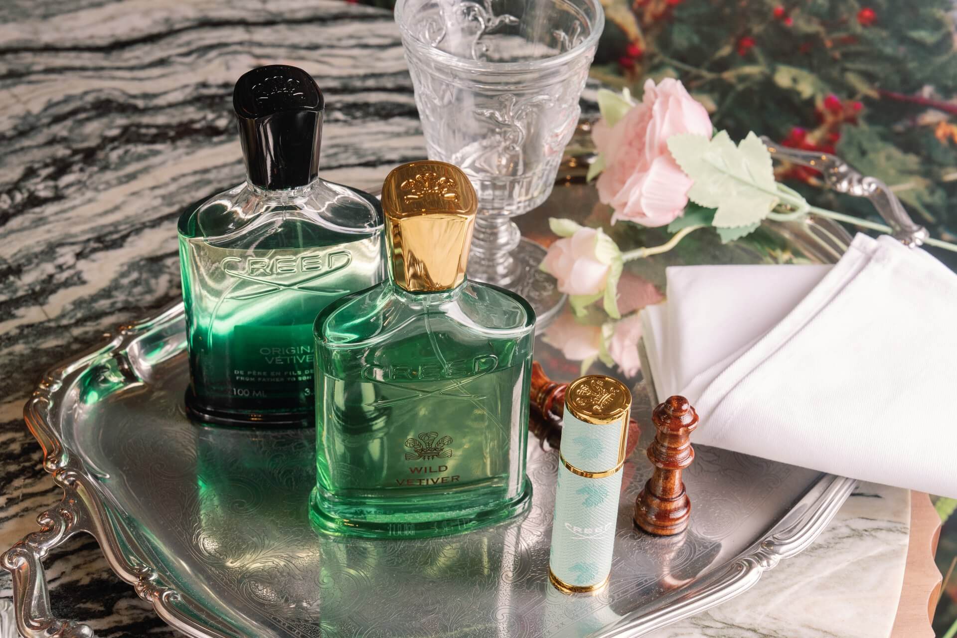 CREED 岩蘭草香水與隨身香置於銀盤與花卉場景,呈現優雅英倫香氛氛圍