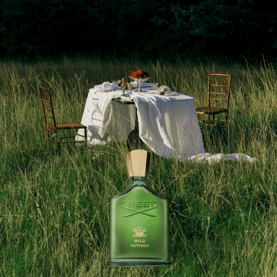 岩蘭野境 Wild Vetiver 香水置於草地戶外餐桌場景,呈現清新木質花香意象