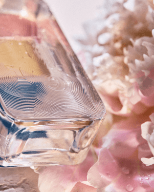 近距離特寫Atelier Cologne Pivoine Nue 無欲裸芍香水瓶與淡粉色芍藥花瓣，呈現大馬士革玫瑰與天竺葵交織出的透明空氣感。